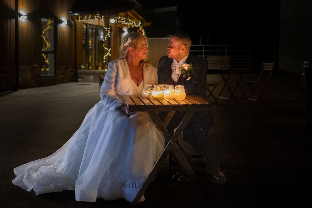 A bride and groom sitting at a table at night.