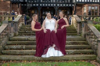 Three bridesmaids posing on steps outdoors at wedding venue.