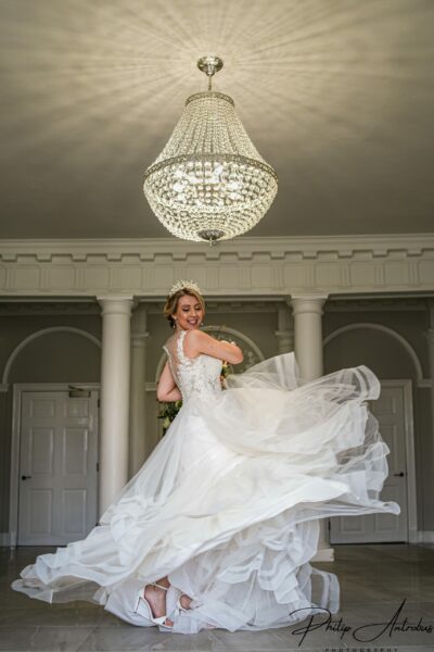 Bride twirling in gown under chandelier.