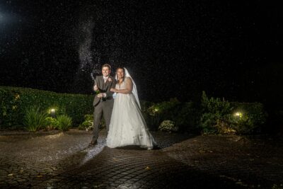 Couple celebrating with champagne at night wedding.