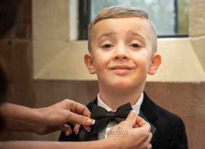 Boy smiling while bow tie is adjusted.