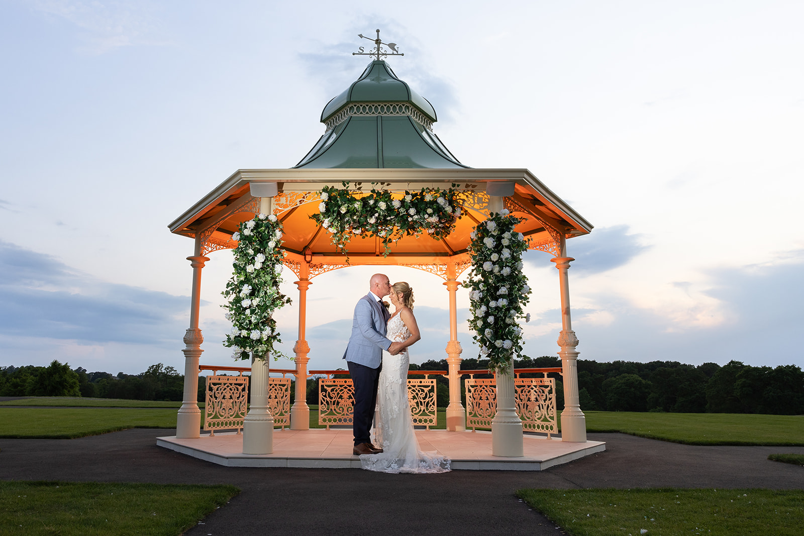 Couple kissing in decorated gazebo at Carden Park in the evening