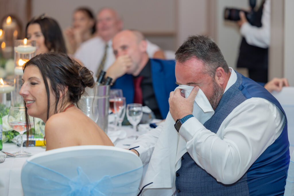 Emotional guest wiping tears at wedding reception at Cheshire wedding venue.