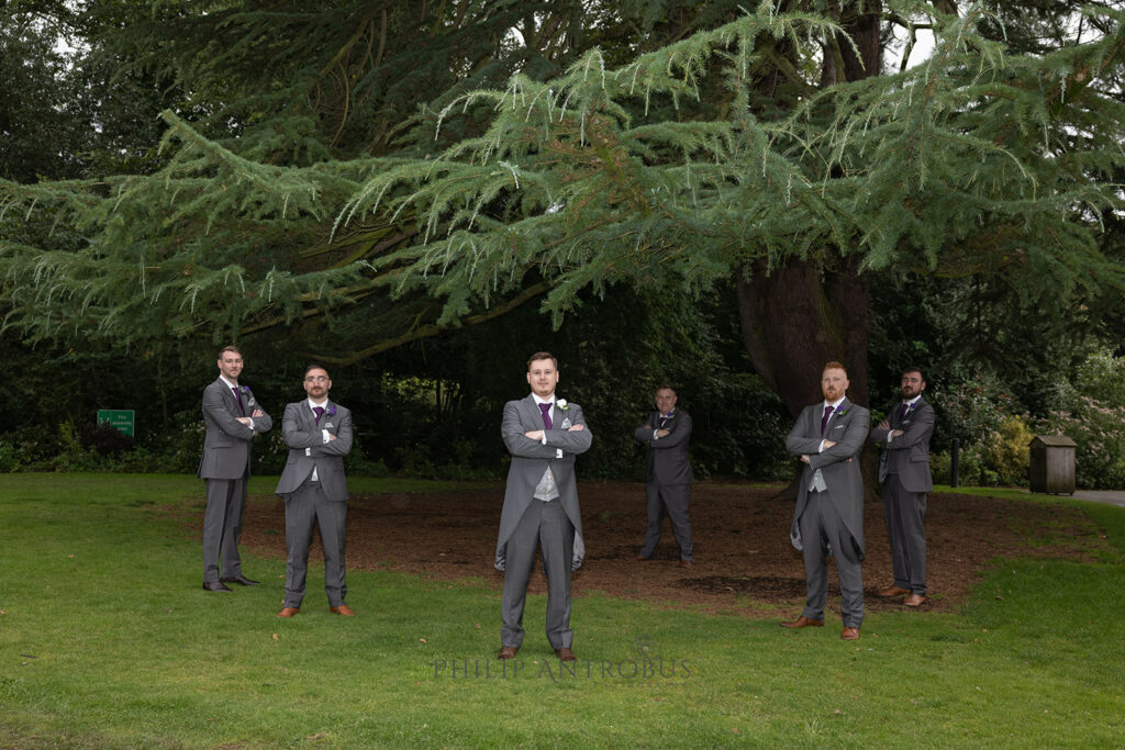 Groomsmen posing in park with conifer tree background at Chester Zoo wedding,