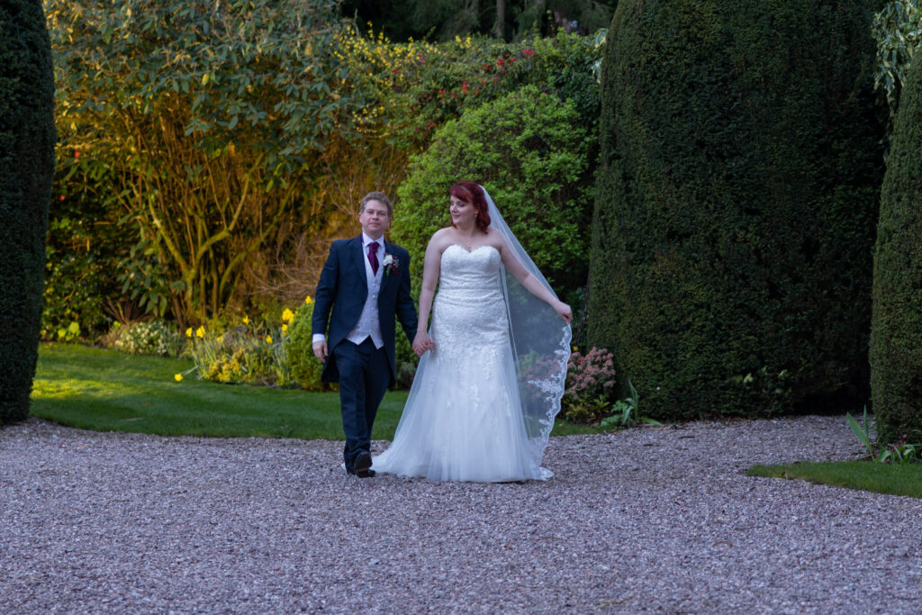 Couple walking in Soughoton Hall gardens after wedding ceremony.