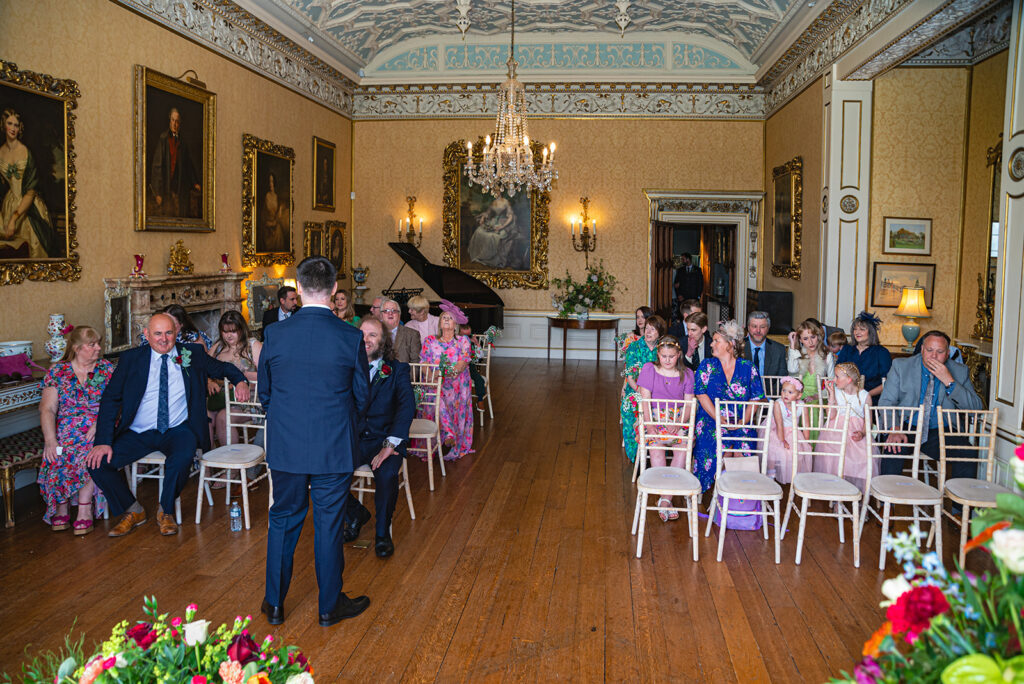Guests seated in ornate room before ceremony.