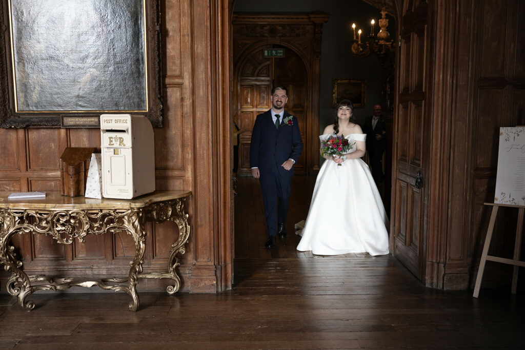 Bride and groom entering wooden panelled room.