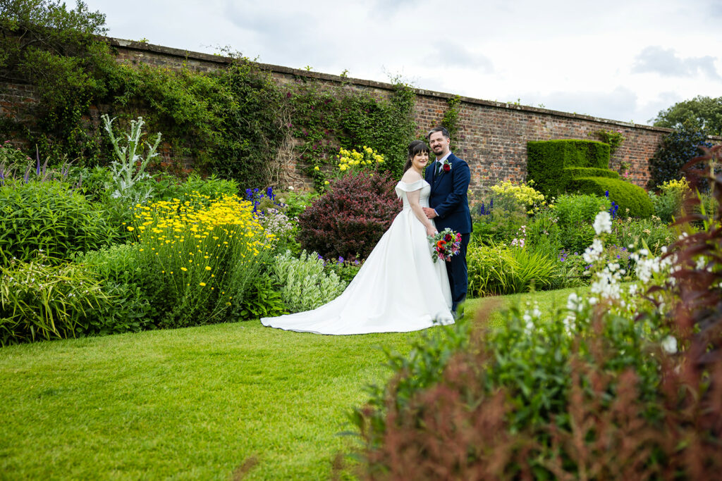 Wedding couple in garden with vibrant flowers.