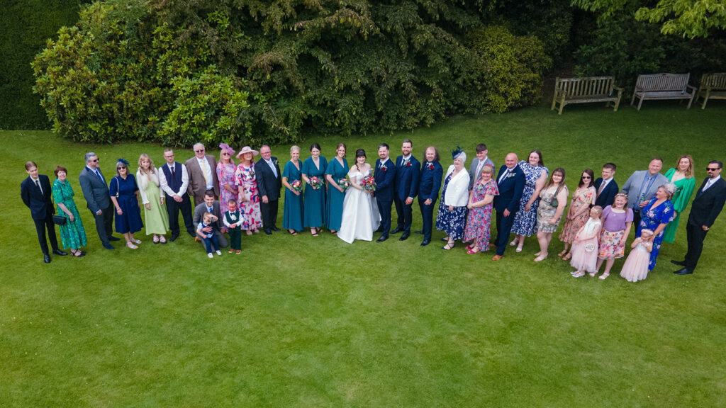Large wedding party photo on green lawn