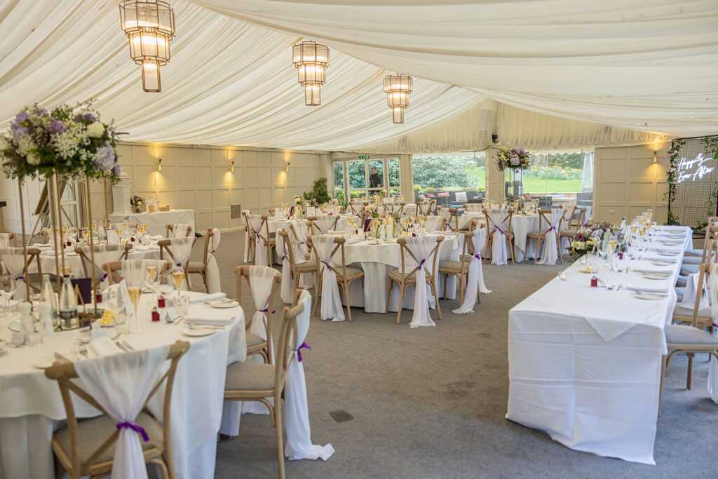 Elegant wedding reception setup in a decorated marquee.