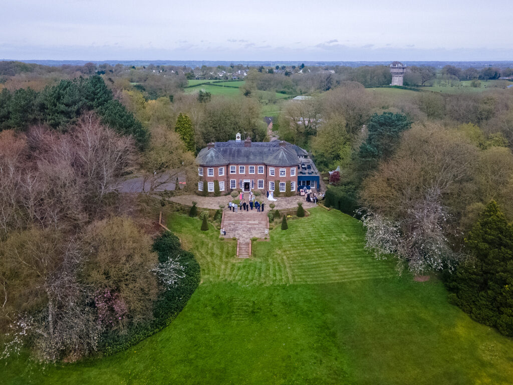 Aerial drone photography at Delamere Manor, with a wedding party gathered on the steps.