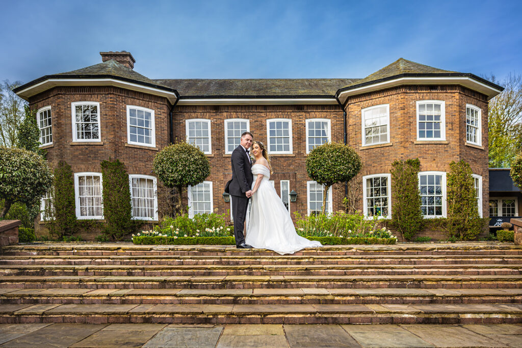Bride and groom outside large house at Delamere Manor