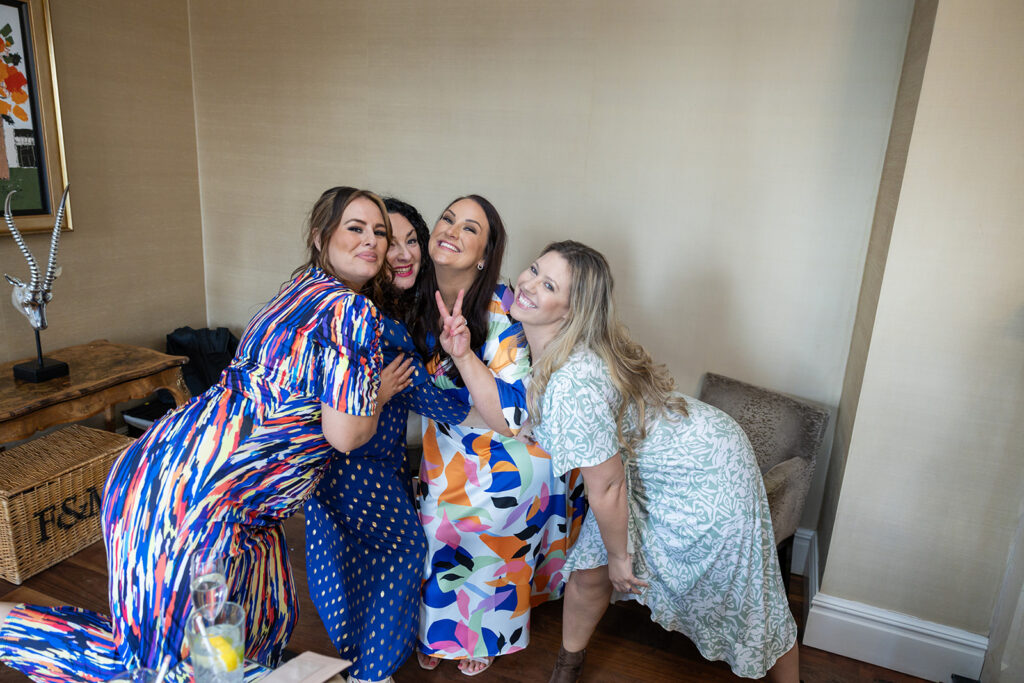 Four women smiling in colourful dresses as wedding at Delamere Manor