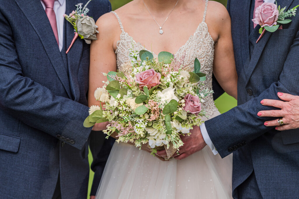 Bride holding bouquet, wedding party in suits.