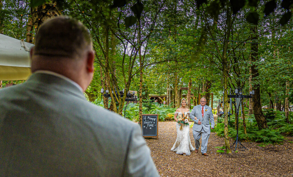 The Groom watching his bride walk down the aisle at outdorr wedding at Cheshire Woodland Weddings.