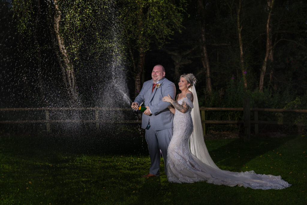 Couple celebrating with champagne outdoors at night.