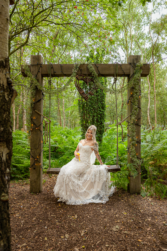Bride on wooden swing in forest setting