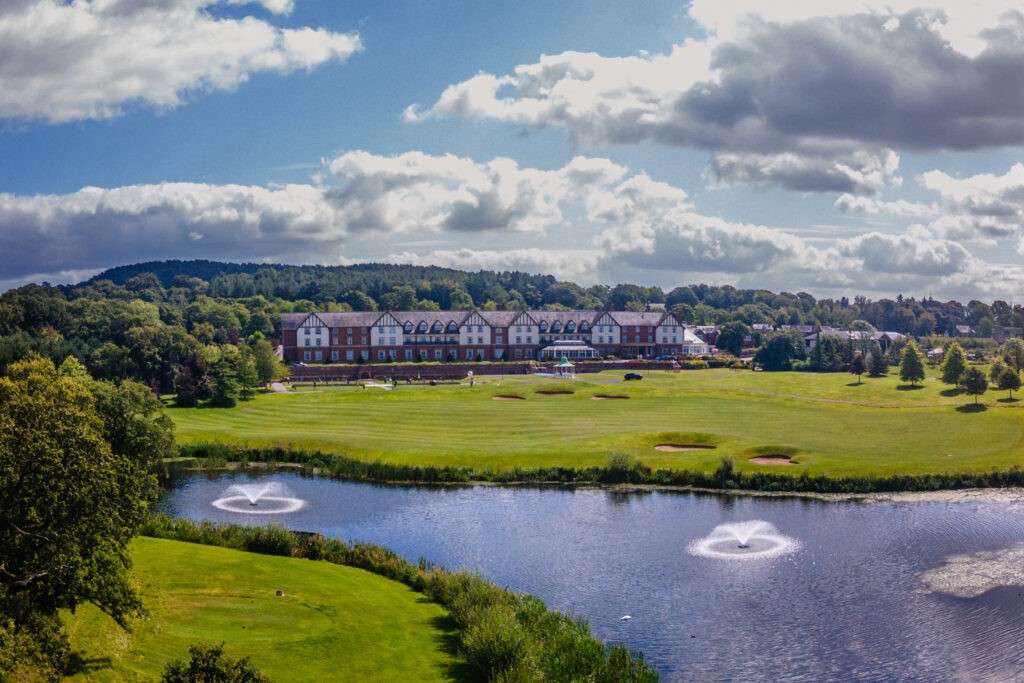 Carden Park Hotel overlooks golf course with fountains in a pond  creating an idyllic setting for a Carden Park Wedding.