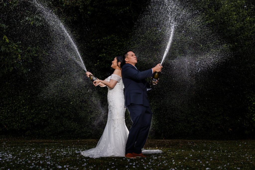 Happy couple spraying champagne outdoors at Warrington Wedding Venue