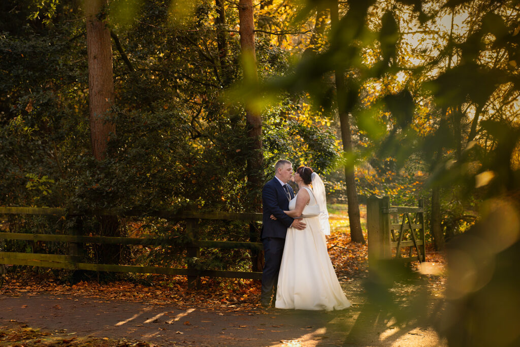 Bride and groom embrace in autumn forest wedding.