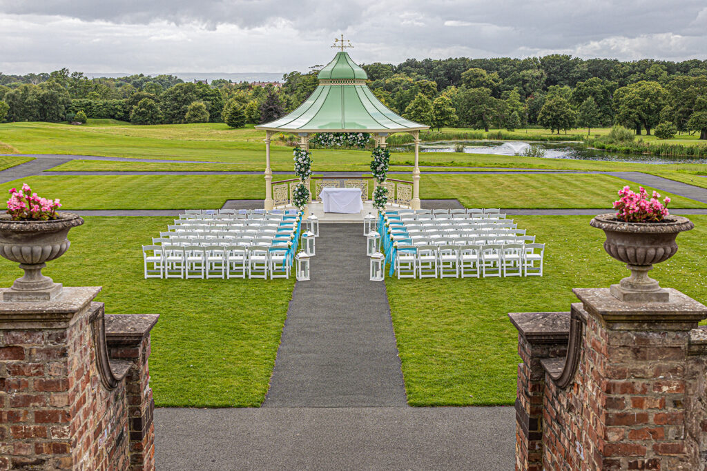 Outdoor wedding ceremony setup with green gazebo at Carden Park Wedding Venue