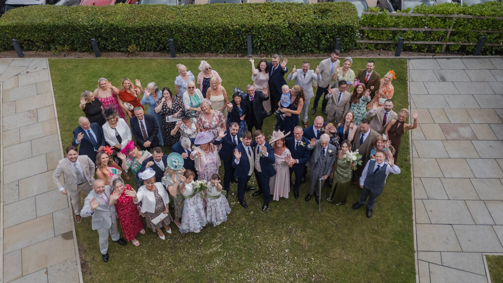Drone photography of large wedding group smiling on lawn at wedding at The Old Palace Chester wedding photography by recommended wedding suppllier Philip Antrobus Wedding Photographer