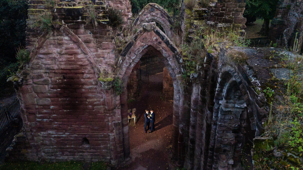 Two people stand in old stone ruins.
