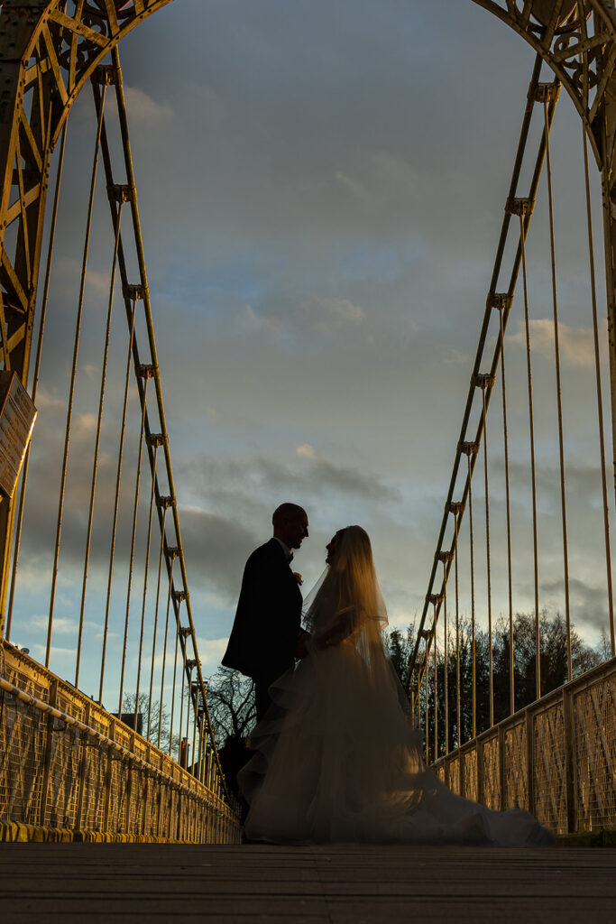 Couple silhouetted on a bridge at sunset.