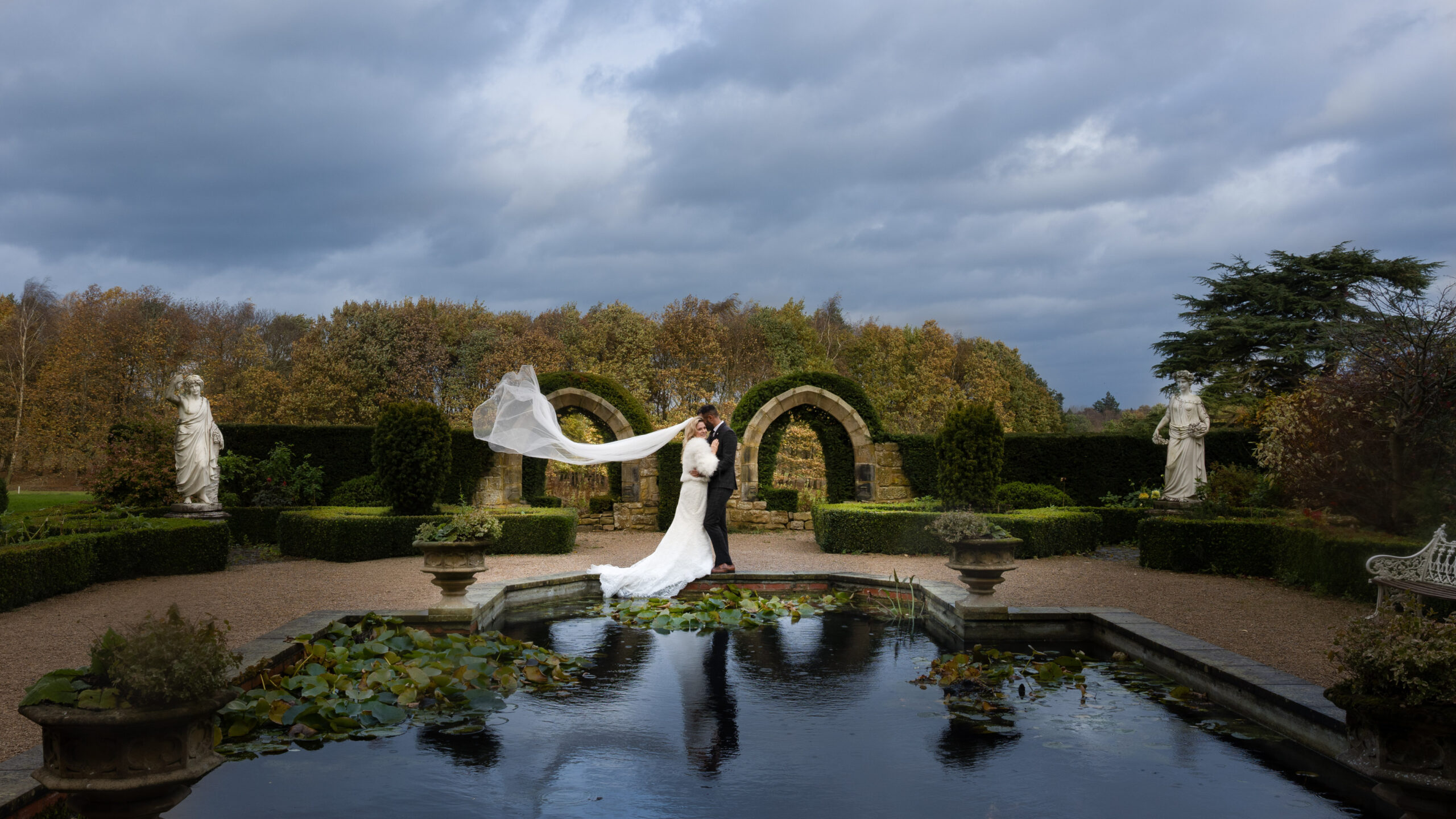 Bride and groom in garden beside pond